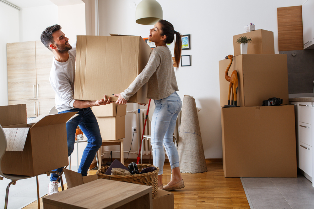 New Homeowners Carrying Moving Boxes Into Their New Kitchen