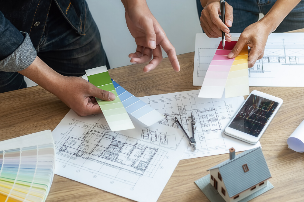 Couple Picking Out Paint Samples With Other Renovation Tools On The Table